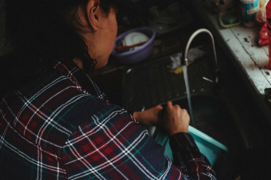 Closeup Shot Of A Female Washing Dishes In The Old Dark Kitchen