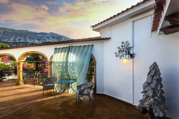 Gorgeous views of the terrace with wind-blown curtains against a mountain backdrop.