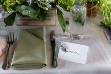Empty name card with a sprig of lavender along with a green and white themed table setting of a bridal shower brunch.