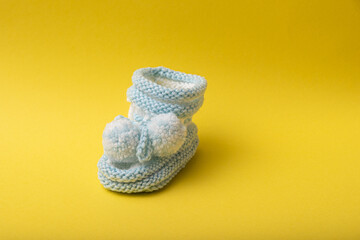 homemade knitted shoes for newborn boys on yellow background