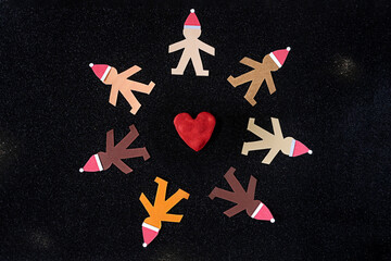 Human multicultural paper puppets at Christmas time wearing Santa's hats and being united in peace....