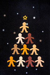 Multiracial human paper puppets forming a triangular Christmas tree on a black background. Can be...