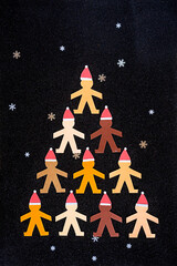 Multiracial human paper puppets wearing Santa's hats and forming a triangular Christmas tree on a...