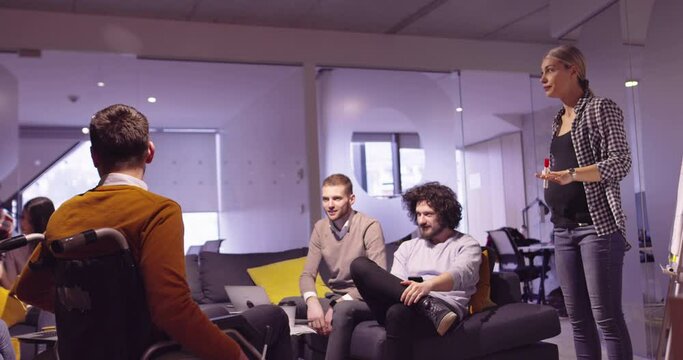 Disabled businessman in a wheelchair at work in modern open space coworking office on team meeting. Effective teamwork and inclusion in a startup business.