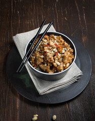 chinese dish. Kung pao, rice with chicken fillet in sauce. Close-up on a dark wooden background, vertical