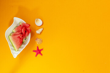 Watermelon on a plate, near seashells and a starfish, on a yellow background, copy space, banner.