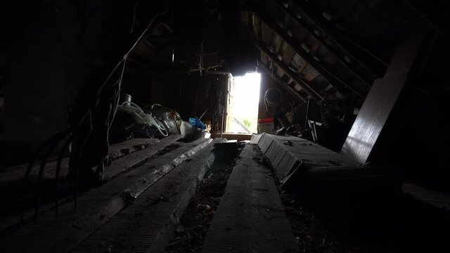 Man walks with pitchfork in a dark attic towards the exit, killer with pitchfork, horror shot for halloween, horror movie