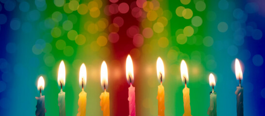 Hanukkah is a Jewish religious holiday of candles. Nine burning candles on bright multicolored...