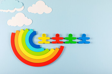 International Children's Day concept. Wooden toy children with rainbow on the bright blue background. Flat lay. Copy space.