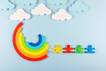 International Children's Day concept. Wooden toy children with rainbow on the bright blue background. Flat lay. Copy space.