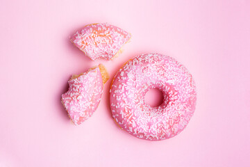 background pink glazed donut on pink background, whole and halved.