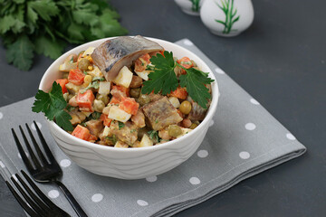 Herring salad with carrots, eggs and peas in a white bowl on a dark gray background