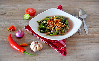 Seaweed vegetable in green and white color, served on the white plate and placed on the brown wooden table