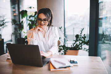 Woman with glasses working on laptop in cafe