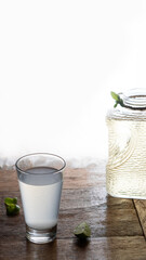 Glass of lemonade. Backlit drink. Piece of lemon on the wooden table.