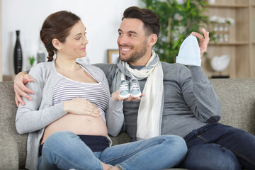 young couple with pregnant woman looking presents children clothes