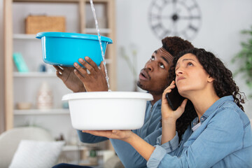 couple sitting in a couch calling insurance for home leaks