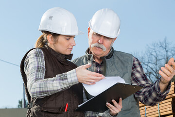 young female and senior worker discussing work outside warehouse