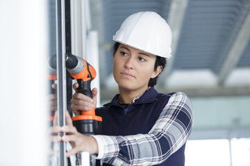 serious woman is drilling a window