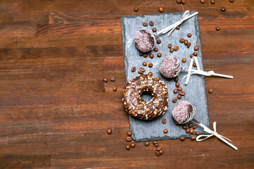 Chocolate cake pops decorated white sprinkles on slate board with doughnut donut coffee beans on wooden background, Delicious pastry, desserts on stick. Tasty food flat lay, lay out