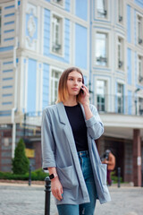 Business woman talking on the phone outdoors. Portrait of beautiful smiling girl in fashionable office clothes. Remote work