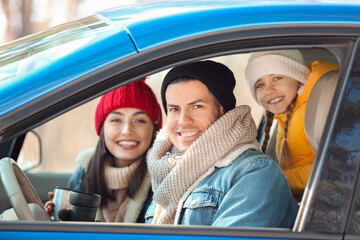 Happy family sitting in car on winter day