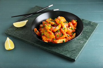 Plate with honey chilli potato on color wooden background
