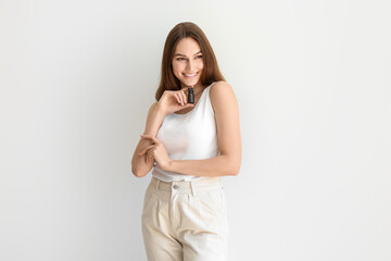 Happy woman holding bottle of natural essential oil on light background