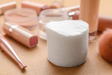 Stack of clean cotton pads and decorative cosmetics on color table, closeup