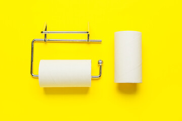 Holder and empty toilet paper tubes on yellow background
