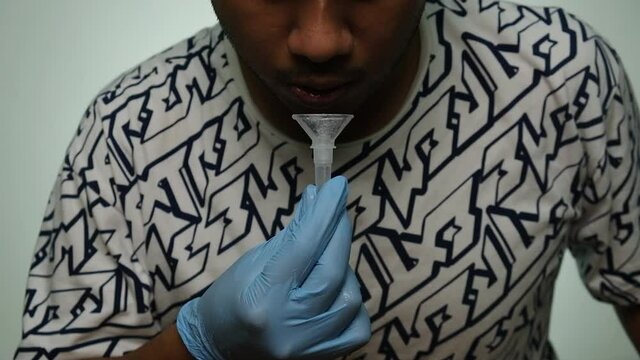 A low light noise effect added footage of men spitting and mix with buffer in the tube for Covid-19 Self test.