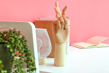 Wooden hand, modern lamp and books on white table
