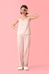 Young woman with cardboard tube from toilet paper on color background