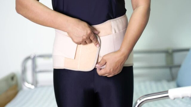 Asian lady patient wearing back pain support belt for orthopedic lumbar.