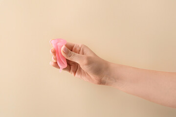 Female hand with menstrual cup on color background