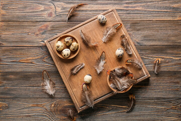 Board with beautiful pheasant feathers and eggs on wooden background