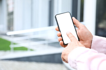 Man typing on mobile phone with blank screen on city street, closeup