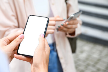 Women using mobile phones on city street, closeup