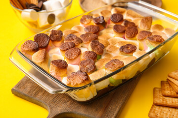 Baking dish with tasty S'mores dip on yellow background, closeup