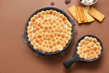 Frying pans with tasty S'mores dip and crackers on color background