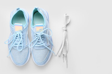 Sportive shoes and laces tied in knot on white background
