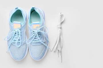 Sportive shoes and laces tied in knot on white background