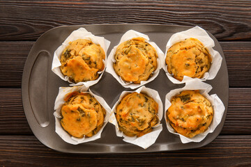 Baking tin with tasty spinach muffins on dark wooden background