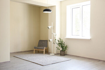 Chair with lamp and houseplant near light wall in big room