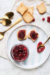 Bowl of tasty cranberry jam and sandwiches on white background