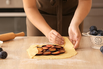 Obraz na płótnie Canvas Woman cooking plum galette at table