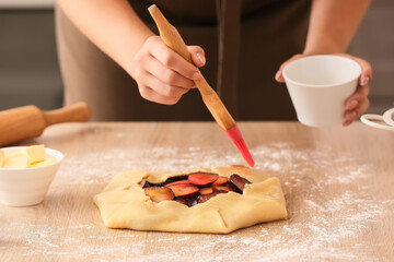 Woman cooking plum galette at table