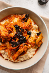Tasty oatmeal, beef stew with prunes and napkin on table, closeup