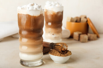 Glasses of iced hojicha latte, chasen and powder on light background