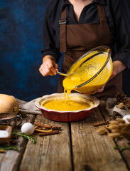 The chef prepares an American pumpkin pie. Spreads the filling onto the dough. Lots of ingredients, decor. Step by step recipe. Cookbook, culinary blog, restaurant, hotel, home cooking.